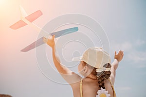 Kid playing with toy airplane. Children dream of travel by plane. Happy child girl has fun in summer vacation by sea and