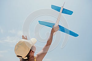 Kid playing with toy airplane. Children dream of travel by plane. Happy child girl has fun in summer vacation by sea and