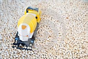 A kid  is playing with a yellow plastic concrete mixer truck toy in the cork pool