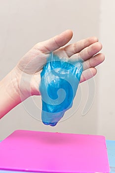 Kid plays with a radiation slime filled with tiny foam beads. Boy stretches slime toy in hands and looks through it