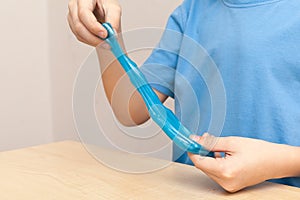 Kid plays with a radiation slime filled with tiny foam beads. Boy stretches slime toy in hands and looks through it