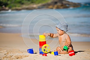 Kid plays with toys at the seashore in summertime