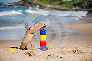 Kid plays with toys at the seashore in summertime