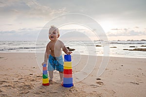 Kid plays with toys at the seashore in summertime