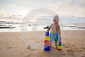 Kid plays with toys at the seashore in summertime