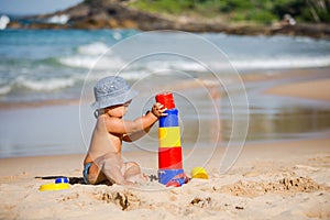 Kid plays with toys at the seashore in summertime