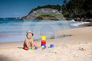 Kid plays with toys at the seashore in summertime