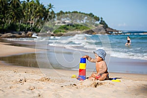 Kid plays with toys at the seashore in summertime