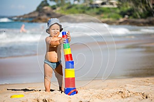 Kid plays with toys at the seashore in summertime