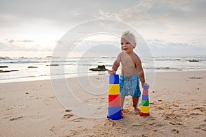 Kid plays with toys at the seashore in summertime