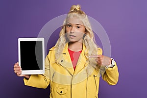 Kid pointing with finger at digital tablet with copy space on purple background