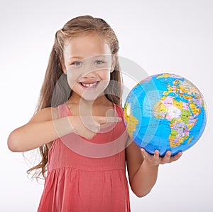 Kid, pointing to globe in studio with world, planets and city for education, geography and portrait. Student, girl child