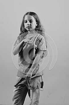 Kid poses as Bgirl in cool style. Girl with serious face on blue background. Childhood and style