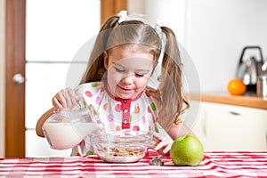 Kid preparing corn flakes with milk photo