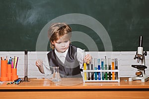 Kid from primary school. It was a little chemistry experiment. Happy little scientist making experiment with test tube