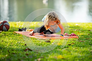 Kid pushing up. Boy doing push up exercise outdoors. Healthy lifestyle in nature. Gymnastic for children.