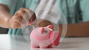 Kid putting coin in piggy bank, saving pocket money, financial literacy for kids