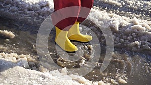 Kid in rainboots jumping in the ice puddle, slow motion