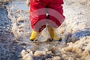 Kid in rainboots jumping in the ice puddle photo