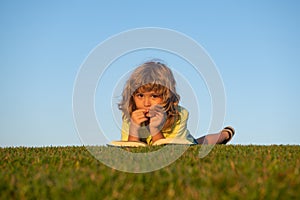 Kid read book in summer park outdoors.