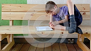 Kid reading a book on a light wooden bench