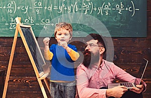 Kid reciting a poem while teacher listens attentively. Cool guy in pink shirt sitting on floor next to standing kid