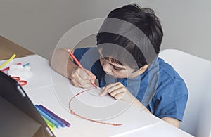 Kid red pen colouring rainbow on paper,Child using digital tablet for homework online lesson,Boy enjoy art activity at home, self- photo