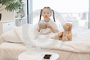 Kid resting in bed with cup because feeling sore throat