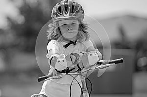 Kid ride bike. Child riding bicycle. Little kid boy in helmet on bicycle along bikeway. Happy cute little boy riding