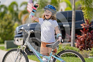 Kid riding bike in a helmet. Child with a childs bike and in protective helmet. Happy kid boy having fun in summer park