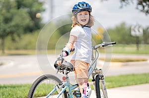 Kid riding bike in a helmet. Child with a childs bike and in protective helmet. Happy kid boy having fun in summer park