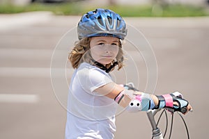 Kid riding on sporty bicycle in summer park. Child in safety helmet riding bike. Boy riding bike outside. Child in