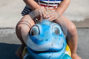 Kid riding on swinging fun animal head with splash water, closeup shot