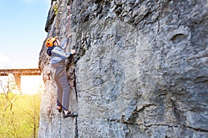 Kid rock climber climbs the cliff.