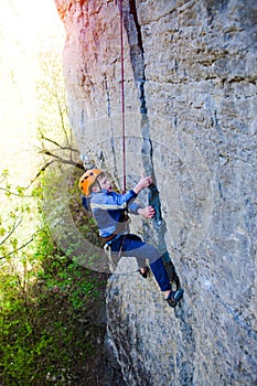 Kid rock climber climbs the cliff.