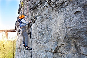 Kid rock climber climbs the cliff.