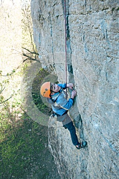 Kid rock climber climbs the cliff.