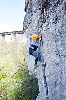 Kid rock climber climbs the cliff.