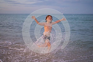 Kid running and splashing in the sea. Summer vacation. Child Running Along the summer beach. Happy excited little kid