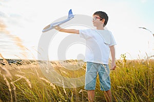 The kid runs with a toy plane. Son dreams of flying. Happy child, boy, runs on the sun playing with a toy airplane on