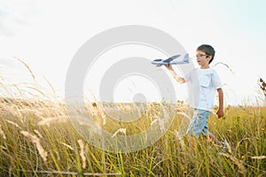 The kid runs with a toy plane. Son dreams of flying. Happy child, boy, runs on the sun playing with a toy airplane on