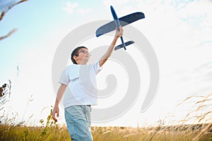 The kid runs with a toy plane. Son dreams of flying. Happy child, boy, runs on the sun playing with a toy airplane on