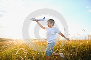 The kid runs with a toy plane. Son dreams of flying. Happy child, boy, runs on the sun playing with a toy airplane on