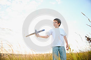 The kid runs with a toy plane. Son dreams of flying. Happy child, boy, runs on the sun playing with a toy airplane on