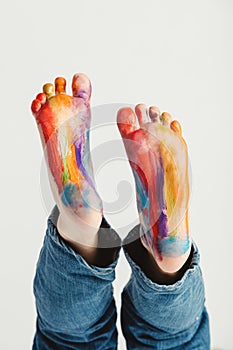 Kid`s feet painted in rainbow colors.