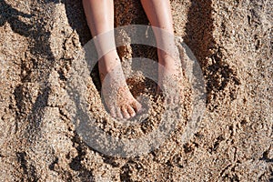 Kid`s feet on the sand on summer day. Barefoot on the beach.