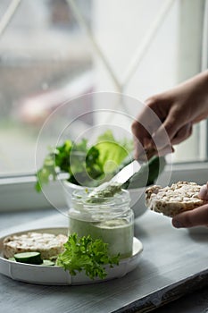 Kid`s hand smeared cream cheese with cucumbers and herbs on toast