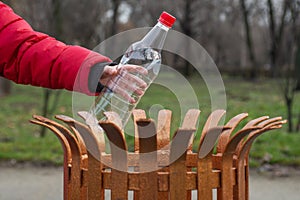 A kid`s hand is throwing away plastic bottle in a recycling bin. Hand throwing empty plastic water bottle in recycling bin