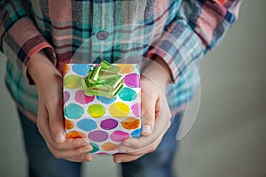 Kid`s hands hold holiday decorated colorful gift box
