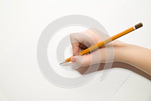 Kid's right hand holding a pencil on over white photo